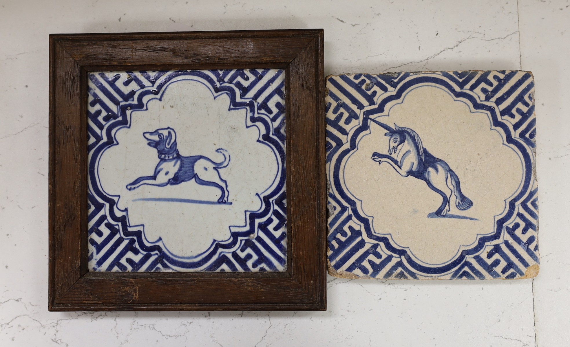 A Delft blue and white ‘dog’ tile, c.1630, framed and a similar unframed unicorn tile (2)